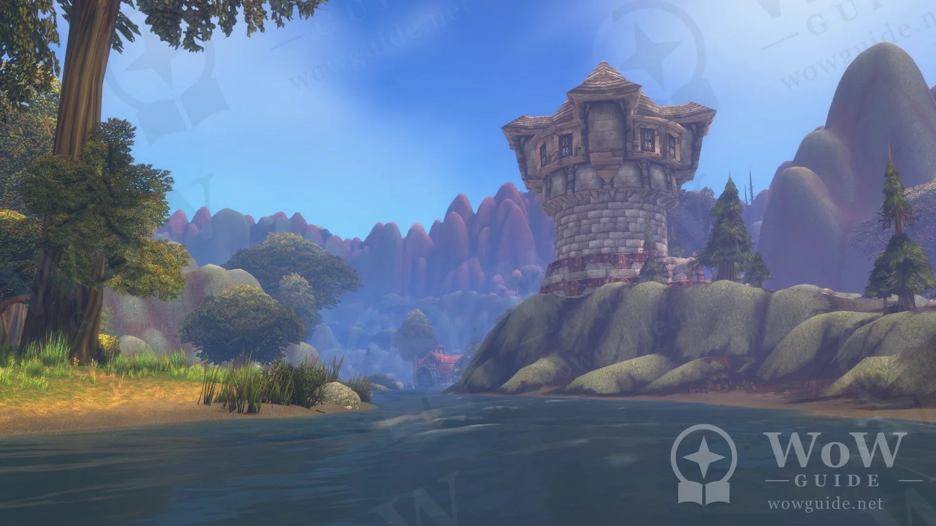 In-game shot of a stone watchtower by a lake with mountains behind it