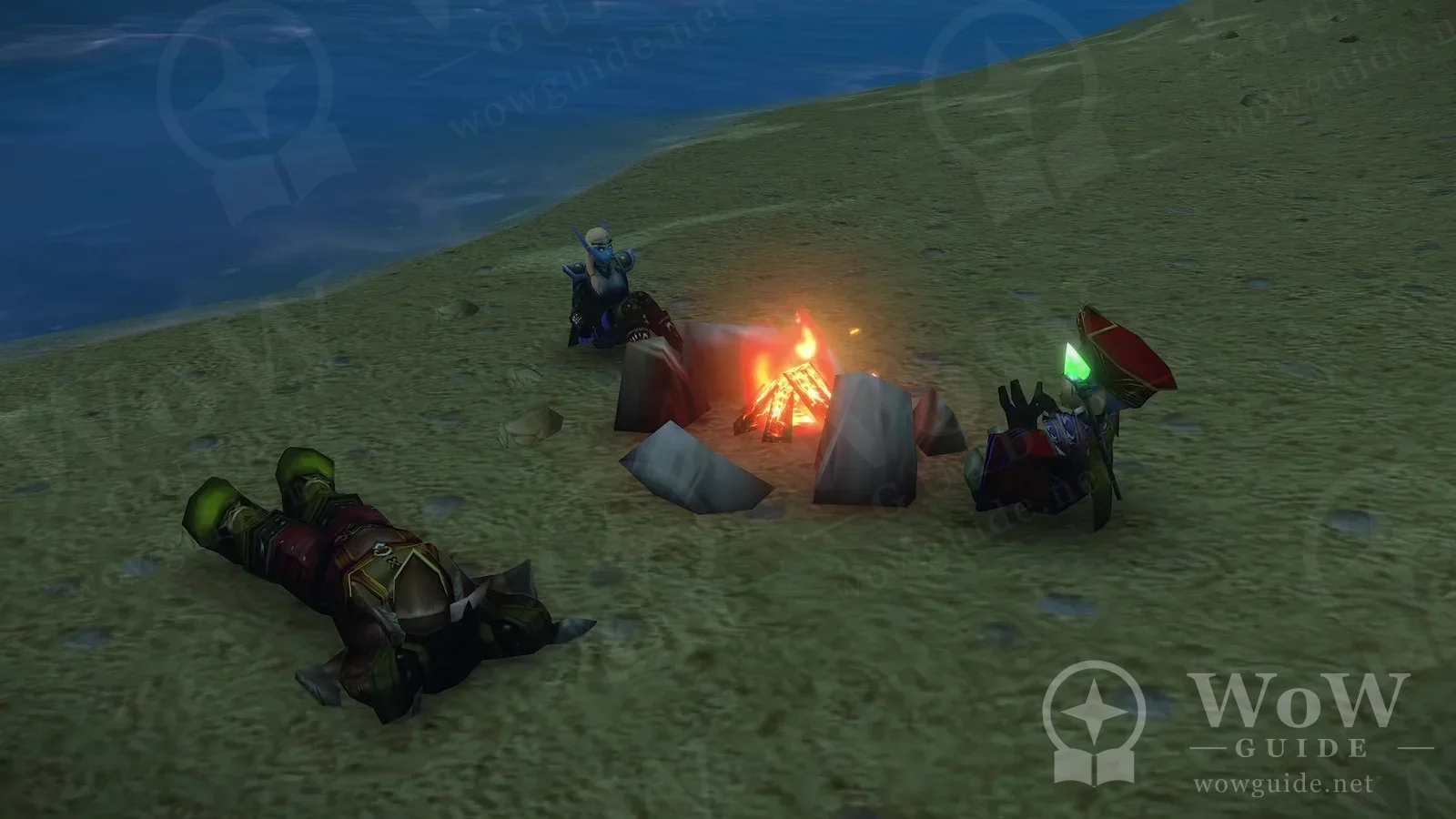 A stone-ringed campfire on a grassy lakeshore; one character is lying on the ground while two others sit by the fire