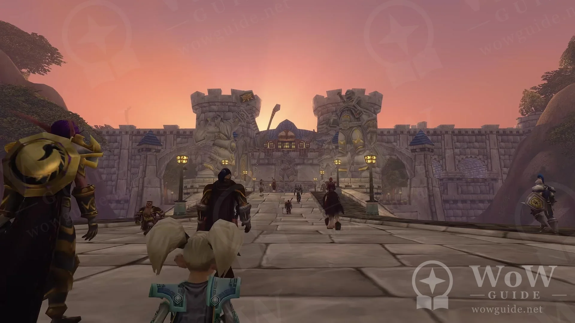 Players walking across a stone bridge towards a large city gate